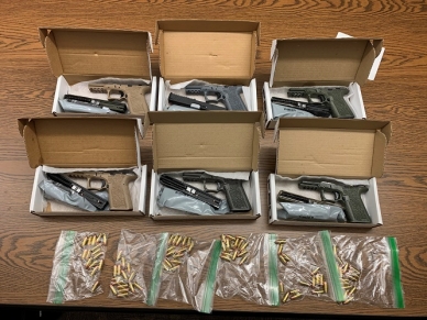 Handguns, bullets and magazines in boxes on a table
