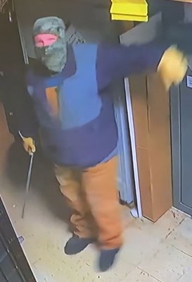 Person standing with face covered and object in hand