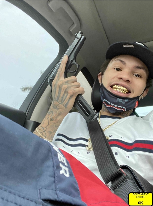A person inside of a vehicle holding a firearm.