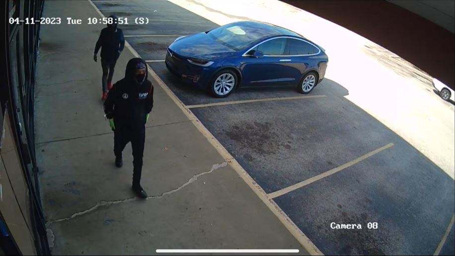 Two people with dark-colored clothing and their hoods up.