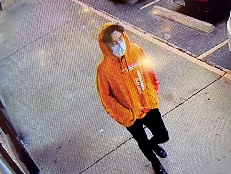 A person with an orange sweatshirt and a face mask.
