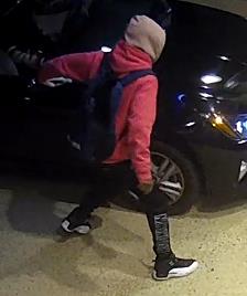 A person in a sweatshirt with a light-colored hood and black and white sneakers.