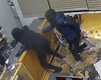 Two people in dark-colored clothing inside of a store.