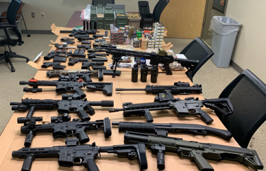 Numerous firearms on a table.