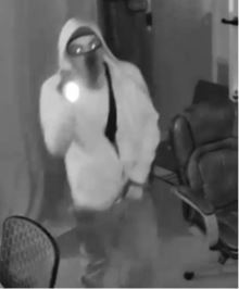 A person in a hooded sweatshirt and mask holding a flashlight.