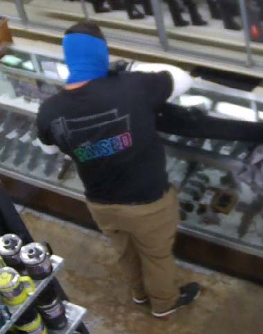 A man with blue material covering his head standing near a glass case.