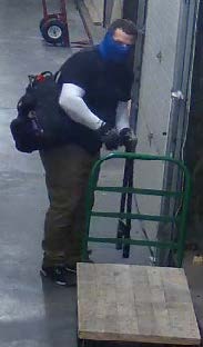A man with blue material partially covering his face standing near a door.
