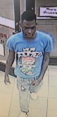 Suspect standing in store with a blue shirt on